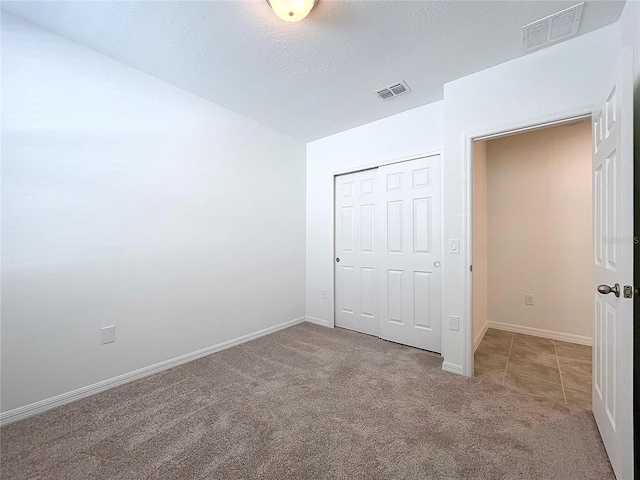 unfurnished bedroom featuring a closet, carpet, and a textured ceiling