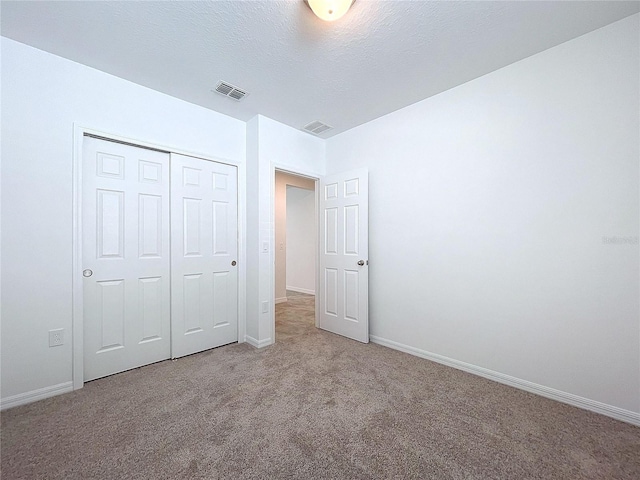 unfurnished bedroom featuring carpet flooring, a textured ceiling, and a closet