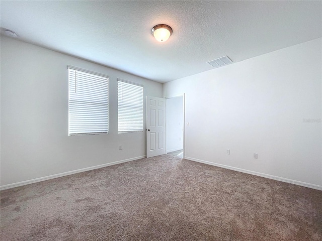 spare room featuring carpet flooring and a textured ceiling