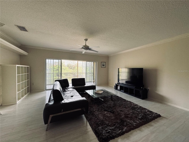 living room featuring a textured ceiling, ornamental molding, ceiling fan, and light wood-type flooring