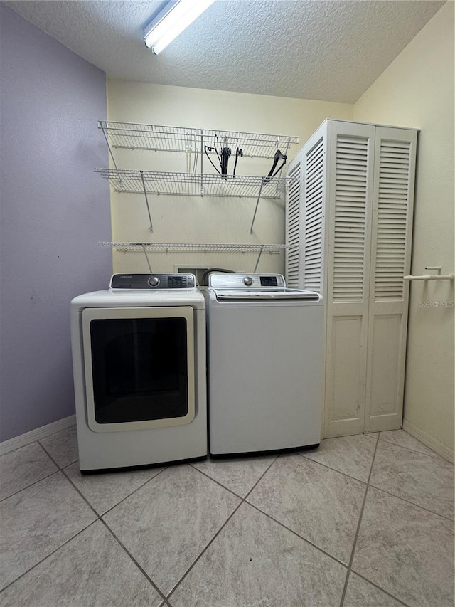 washroom featuring washer and clothes dryer, a textured ceiling, and light tile patterned floors