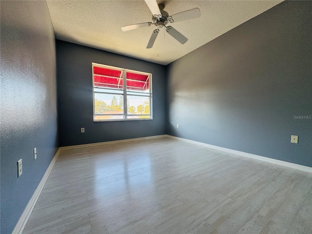 empty room with ceiling fan, light wood-type flooring, and a textured ceiling