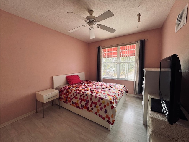 bedroom featuring a textured ceiling, ceiling fan, and light wood-type flooring