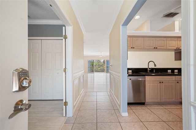 kitchen with sink, ornamental molding, dishwasher, and light tile patterned flooring