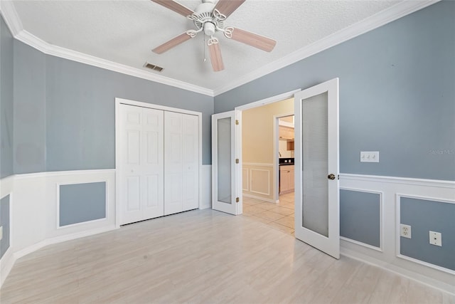 unfurnished bedroom featuring ornamental molding, light hardwood / wood-style floors, a closet, and a textured ceiling