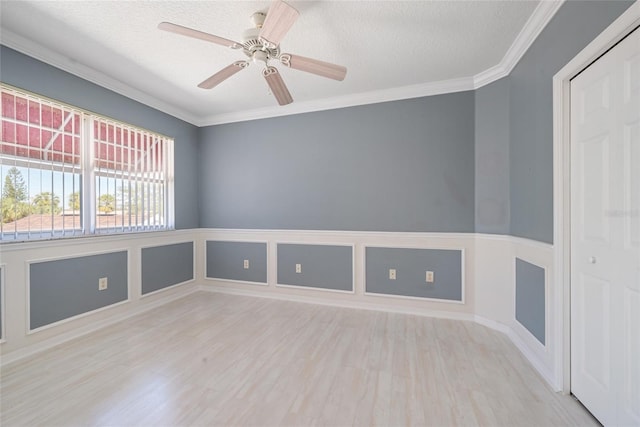 empty room with ornamental molding, ceiling fan, a textured ceiling, and light hardwood / wood-style flooring