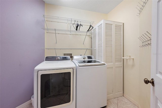 laundry room with light tile patterned floors, washer and clothes dryer, and a textured ceiling