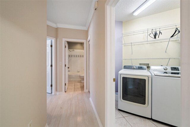 washroom featuring crown molding, washer and dryer, a textured ceiling, and light tile patterned flooring