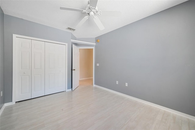 unfurnished bedroom featuring ceiling fan, a closet, light hardwood / wood-style flooring, and a textured ceiling