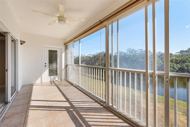 unfurnished sunroom with ceiling fan and a water view