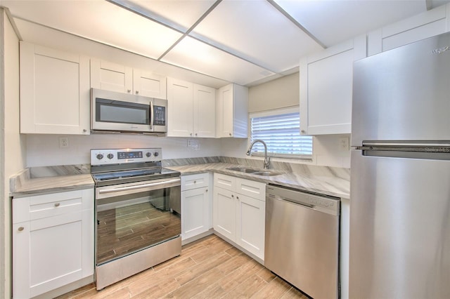 kitchen featuring light stone countertops, white cabinetry, sink, and appliances with stainless steel finishes