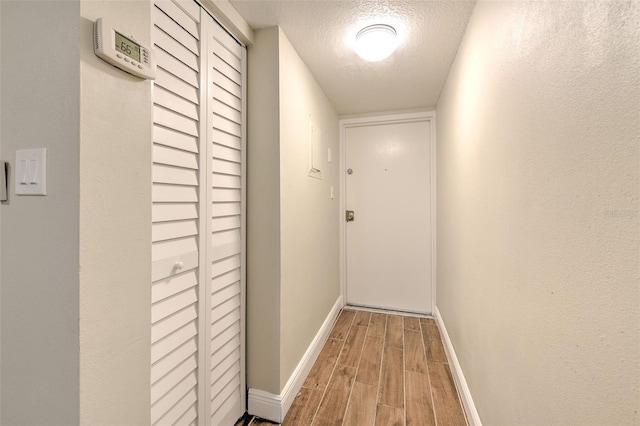 hallway with wood-type flooring and a textured ceiling