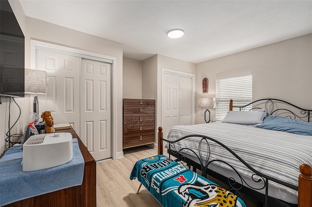 bedroom with light hardwood / wood-style floors and two closets