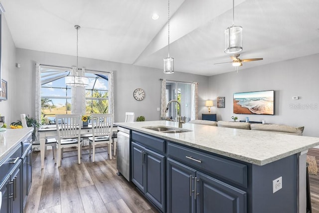 kitchen featuring dark hardwood / wood-style flooring, stainless steel dishwasher, sink, blue cabinetry, and an island with sink