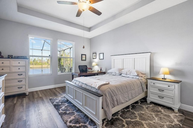 bedroom with ceiling fan, dark hardwood / wood-style flooring, and a raised ceiling