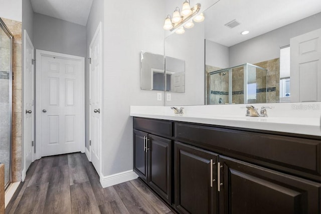 bathroom with hardwood / wood-style floors, vanity, and a shower with shower door