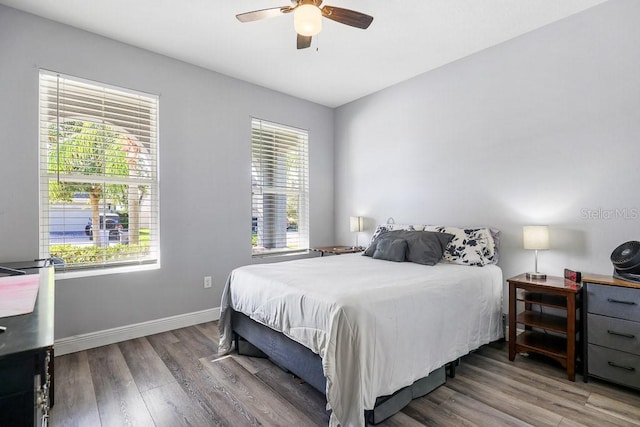 bedroom with ceiling fan, wood-type flooring, and multiple windows