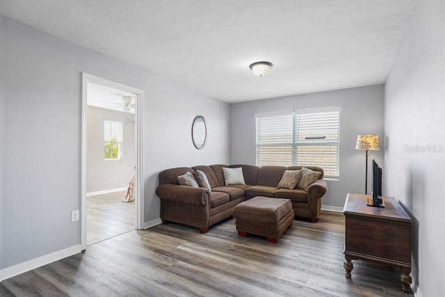 living room featuring a textured ceiling, plenty of natural light, dark wood-type flooring, and ceiling fan