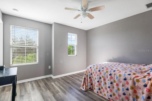 bedroom featuring hardwood / wood-style flooring, ceiling fan, and multiple windows