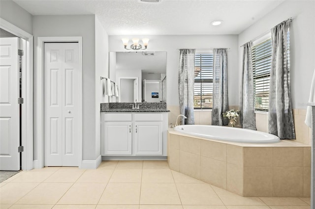 bathroom featuring tiled tub, tile patterned flooring, vanity, and an inviting chandelier