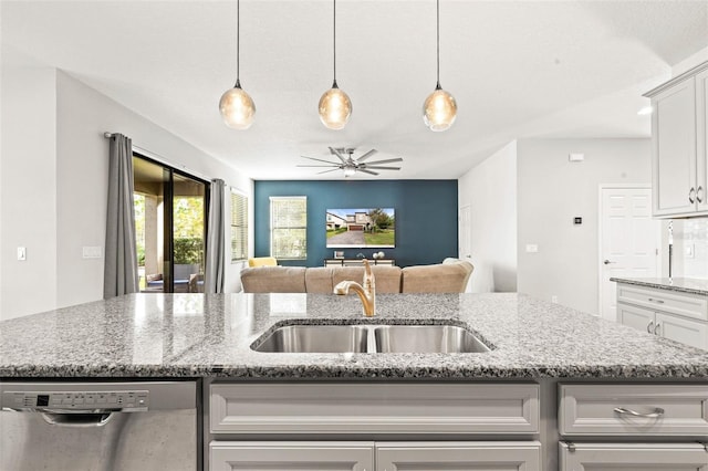 kitchen featuring light stone countertops, stainless steel dishwasher, ceiling fan, sink, and an island with sink