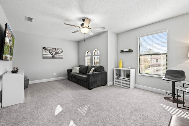 living room with a textured ceiling, light colored carpet, and ceiling fan