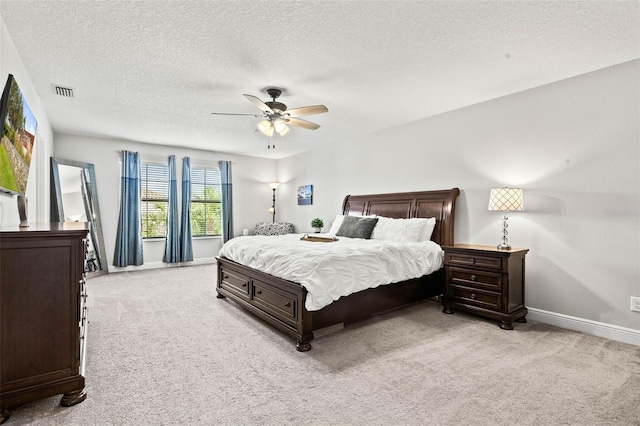 carpeted bedroom featuring ceiling fan and a textured ceiling