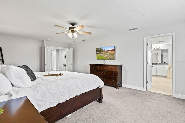 bedroom featuring a textured ceiling, ceiling fan, light carpet, and ensuite bath