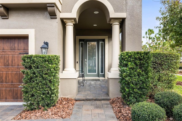 entrance to property featuring a garage and stucco siding