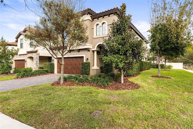 mediterranean / spanish-style home with driveway, an attached garage, stucco siding, a front lawn, and a tile roof