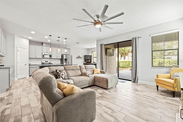 living area featuring ceiling fan, recessed lighting, light wood finished floors, and a textured ceiling