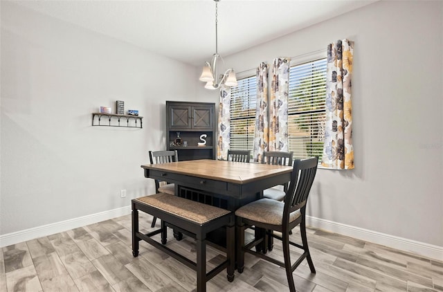 dining space with baseboards, an inviting chandelier, and light wood-style flooring