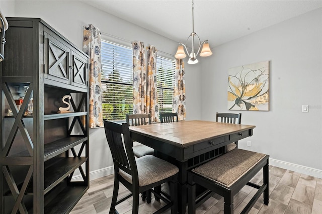 dining room featuring a notable chandelier, baseboards, and light wood finished floors