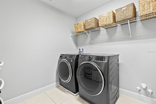 laundry area featuring laundry area, light tile patterned floors, separate washer and dryer, and baseboards