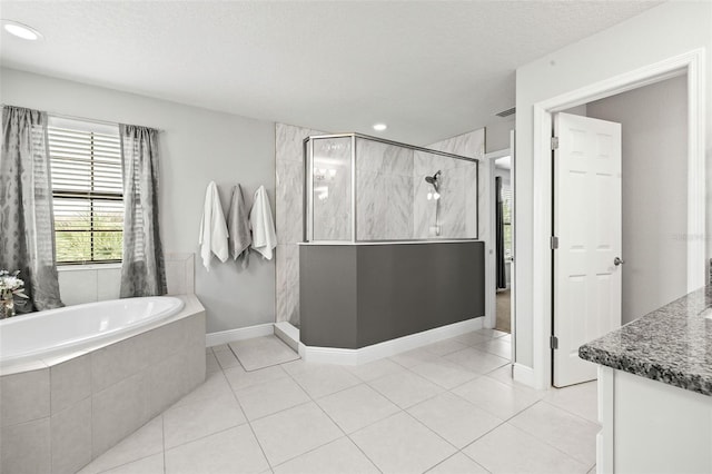 bathroom with tile patterned floors, a stall shower, a textured ceiling, and a garden tub