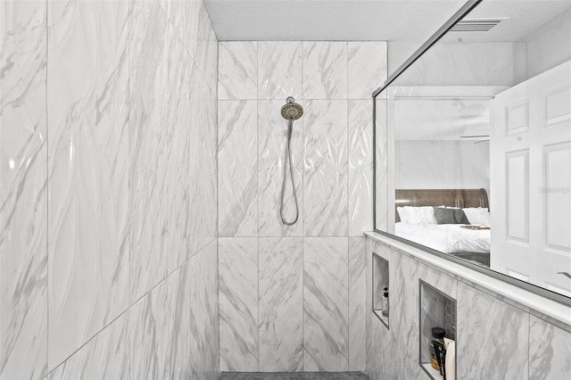 ensuite bathroom featuring visible vents, tiled shower, a textured ceiling, and ensuite bathroom