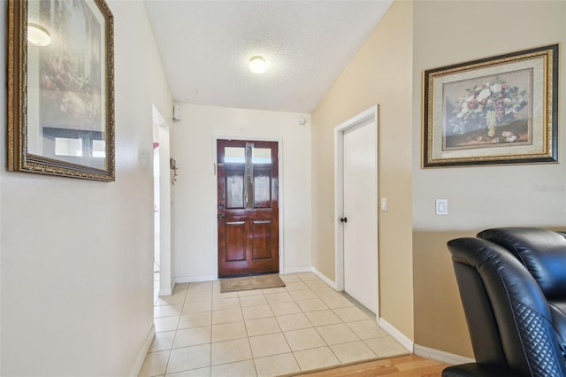 foyer entrance with a textured ceiling, light tile patterned floors, and vaulted ceiling