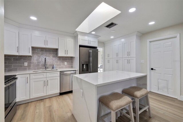 kitchen featuring white cabinets, a center island, sink, and appliances with stainless steel finishes