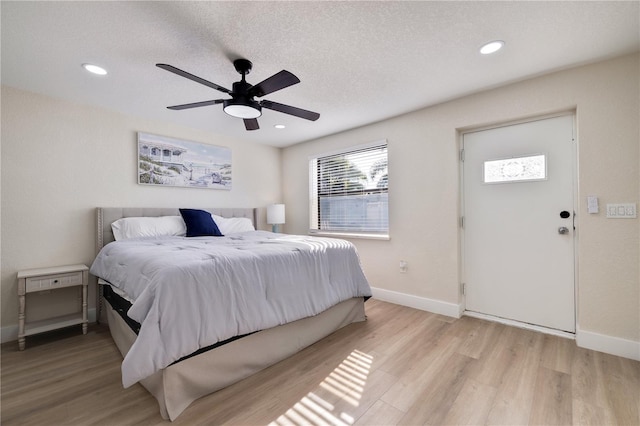 bedroom with a textured ceiling, light wood-type flooring, and ceiling fan