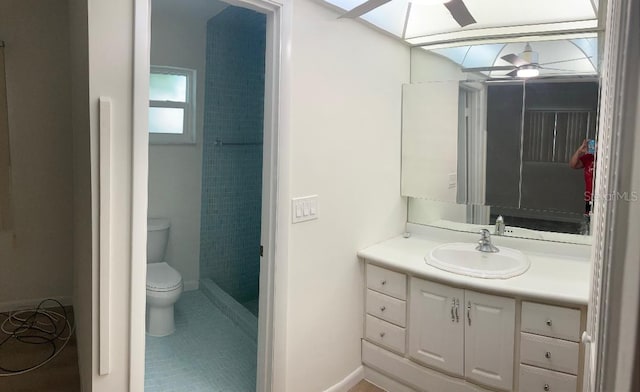 bathroom with a skylight, vanity, ceiling fan, tile patterned flooring, and toilet