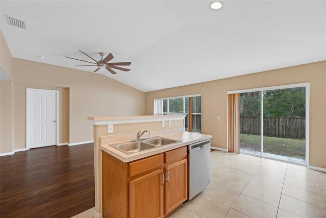 kitchen with sink, vaulted ceiling, stainless steel dishwasher, light tile patterned floors, and an island with sink