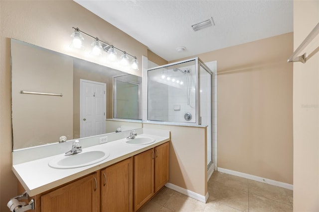 bathroom with a textured ceiling, vanity, tile patterned floors, and a shower with shower door