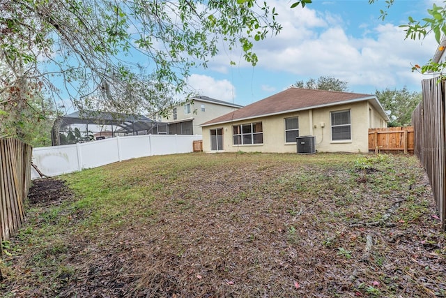 back of property featuring central air condition unit and a lawn