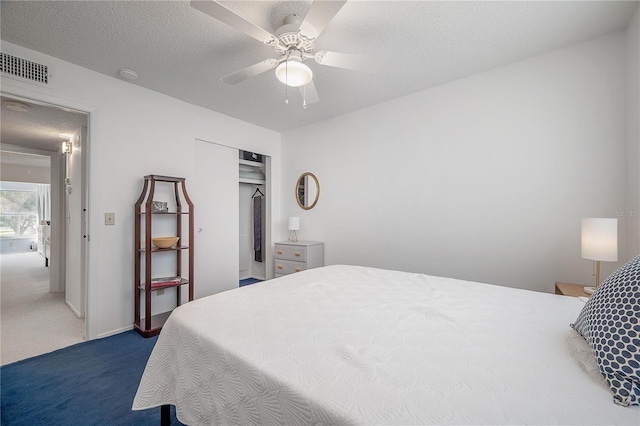 carpeted bedroom with a textured ceiling, a closet, and ceiling fan