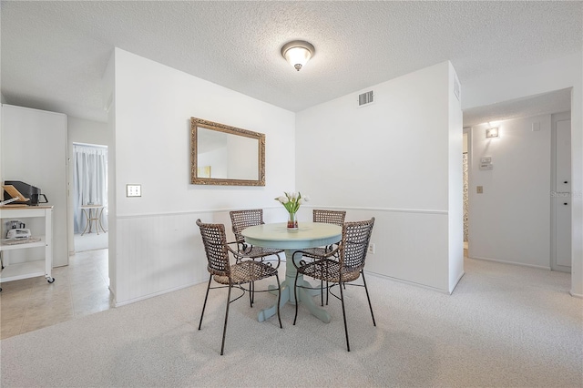 dining area featuring light carpet and a textured ceiling