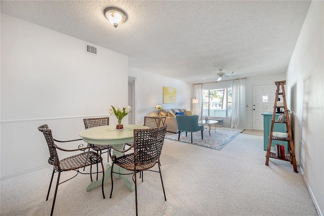 carpeted dining room with ceiling fan and a textured ceiling