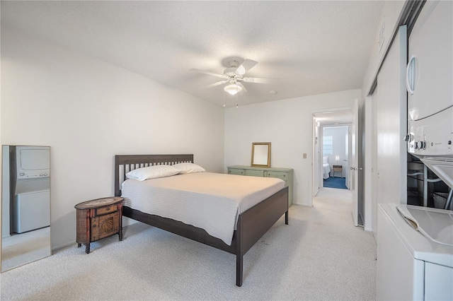 carpeted bedroom with a textured ceiling, stacked washing maching and dryer, and ceiling fan