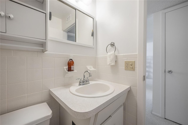 bathroom featuring vanity, a textured ceiling, toilet, and tile walls