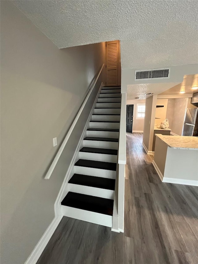 stairway featuring hardwood / wood-style floors and a textured ceiling