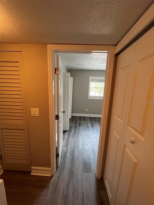 corridor featuring dark hardwood / wood-style flooring and a textured ceiling